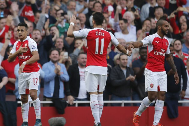 Arsenal's Alexis Sanchez, with teammates Arsenal's Mesut Ozil, centre and Arsenal's Theo Walcott celebrate after Sanchez scored his second goal and Arsenal's third goal during the English Premier League soccer match between Arsenal and Manchester United at Emirates stadium in London, Sunday, Oct. 4, 2015.(AP Photo/Frank Augstein)