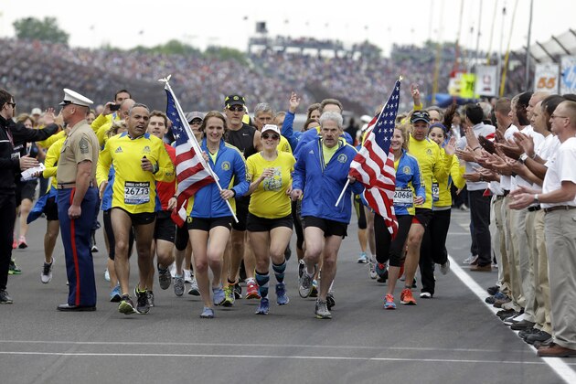 A group of the approximately 35 runners from the 2013 Boston Marathon, unable to finish the race due to the tragic bombings, complete the distance by crossing finish line at the Indianapolis Motor Speedway before the start of the 97th Indianapolis 500 auto race. (AP Photo/Michael Conroy)