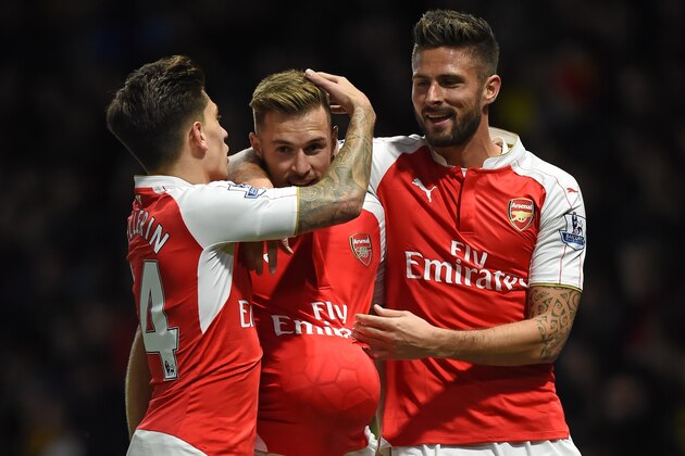 Arsenal's Welsh midfielder Aaron Ramsey (C) celebrates with Arsenal's Spanish defender Hector Bellerin and Arsenal's French striker Olivier Giroud (R) after scoring their third goal during the English Premier League football match between Watford and Arsenal at Vicarage Road Stadium in Watford, north of London on October 17, 2015. AFP PHOTO / PAUL ELLIS

RESTRICTED TO EDITORIAL USE. No use with unauthorized audio, video, data, fixture lists, club/league logos or 'live' services. Online in-match use limited to 75 images, no video emulation. No use in betting, games or single club/league/player publications.        (Photo credit should read PAUL ELLIS/AFP/Getty Images)