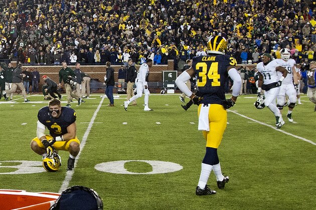 Michigan linebacker Desmond Morgan (3) and defensive back Jeremy Clark (34) react  as Michigan State players rush the field in celebration after an NCAA college football game in Ann Arbor, Mich., Saturday, Oct. 17, 2015. Michigan State won 27-23. (AP Photo/Tony Ding)