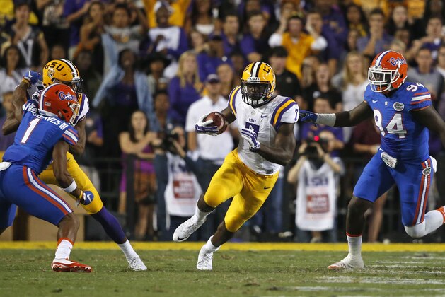 LSU running back Leonard Fournette (7) carries between Florida defensive back Vernon Hargreaves III (1) and defensive lineman Bryan Cox Jr. (94) in the first half of an NCAA college football game in Baton Rouge, La., Saturday, Oct. 17, 2015. (AP Photo/Gerald Herbert)