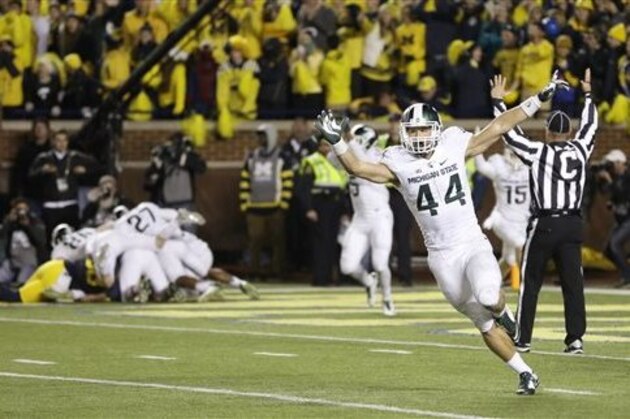 Michigan State safety Grayson Miller (44) celebrates as teammates jump on defensive back Jalen Watts-Jackson after Watts-Jackson recovered a fumbled snap on a punt in the closing seconds of the second half of an NCAA college football game, Saturday, Oct. 17, 2015, in Ann Arbor, Mich. Watts-Jackson lumbered 38 yards for a touchdown on the final play of the game, giving No. 7 Michigan State a shocking 27-23 win over No. 12 Michigan. (AP Photo/Carlos Osorio)