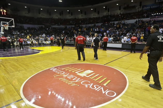 Security guards line the side of the basketball court at the Valley View Casino Center after NBA officials determined the court was too dangerous to continue play of the NBA preseason basketball game between the Los Angeles Lakers and Golden State Warriors in the third quarter Saturday, Oct. 17, 2015, in San Diego. The court had become slippery from moisture on the court caused by the ice from the hockey arena underneath the basketball floor.  (AP Photo/Lenny Ignelzi)