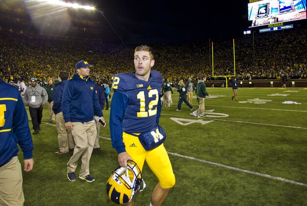 Michigan punter Blake O'Neill (12) walks off the field after an NCAA college football game against Michigan State in Ann Arbor, Mich., Saturday, Oct. 17, 2015. Michigan State's Jalen Watts-Jackson grabbed a flubbed punt by O'Neill and lumbered 38 yards into the end zone for a touchdown on the final play of the game, giving No. 7 Michigan State a shocking 27-23 win over No. 12 Michigan.  (AP Photo/Tony Ding)