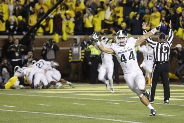 Michigan State safety Grayson Miller (44) celebrates as teammates jump on defensive back Jalen Watts-Jackson after Watts-Jackson recovered a fumbled snap on a punt in the closing seconds of the second half of an NCAA college football game, Saturday, Oct. 17, 2015, in Ann Arbor, Mich. Watts-Jackson lumbered 38 yards for a touchdown on the final play of the game, giving No. 7 Michigan State a shocking 27-23 win over No. 12 Michigan. (AP Photo/Carlos Osorio)