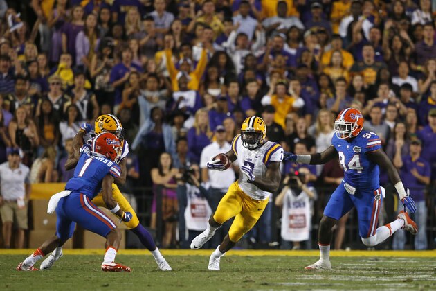 LSU running back Leonard Fournette (7) carries between Florida defensive back Vernon Hargreaves III (1) and defensive lineman Bryan Cox Jr. (94) in the first half of an NCAA college football game in Baton Rouge, La., Saturday, Oct. 17, 2015. (AP Photo/Gerald Herbert)