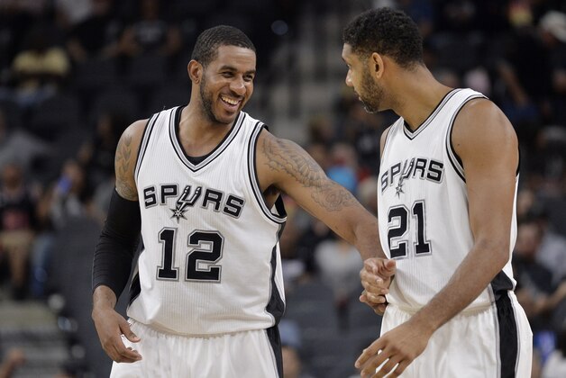 San Antonio Spurs' LaMarcus Aldridge (12) laughs with teammate Tim Duncan during the second half of a preseason NBA basketball game against the Detroit Pistons, Sunday, Oct. 18, 2015, in San Antonio. (AP Photo/Darren Abate)