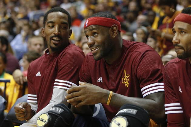 Cleveland Cavaliers forward LeBron James, center, smiles alongside guard J.R. Smith, left, as they sit on the bench in the second half of an NBA preseason basketball game against the Atlanta Hawks, Wednesday, Oct. 7, 2015, in Cincinnati. The Hawks won 98-96. (AP Photo/John Minchillo)
