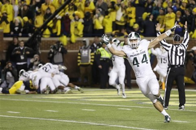 Michigan State safety Grayson Miller (44) celebrates as teammates jump on defensive back Jalen Watts-Jackson after Watts-Jackson recovered a fumbled snap on a punt in the closing seconds of the second half of an NCAA college football game, Saturday, Oct. 17, 2015, in Ann Arbor, Mich. Watts-Jackson lumbered 38 yards for a touchdown on the final play of the game, giving No. 7 Michigan State a shocking 27-23 win over No. 12 Michigan. (AP Photo/Carlos Osorio)
