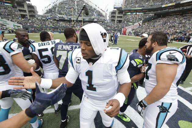 Carolina Panthers quarterback Cam Newton (1) greets players after the coin flip before an NFL football game against the Seattle Seahawks, Sunday, Oct. 18, 2015, in Seattle. (AP Photo/Elaine Thompson)