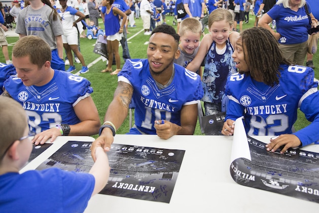 Joshua Rice, 6, left, shakes hands with Kentucky wide receiver Thaddeus Snodgrass while Davis Mainord, 7, and his sister Maecee, 10, meet wide receiver T.V. Williams during the annual NCAA college football Fan Day in Lexington, Ky., Saturday, Aug.8, 2015. (AP Photo/ David Stephenson)