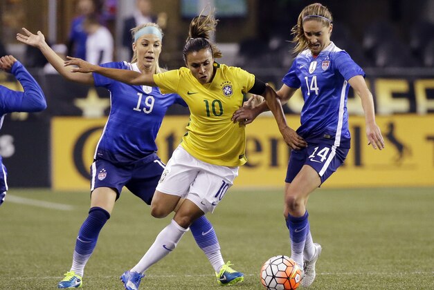 Brazil's Marta (10) works to get to the ball between the United States' Julie Johnston (19) and Morgan Brian (14) during the first half of an international friendly soccer match Wednesday, Oct. 21, 2015, in Seattle. (AP Photo/Elaine Thompson)