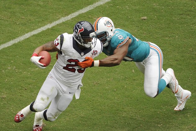 Miami Dolphins linebacker Cameron Wake (91) is dragged by Houston Texans running back Arian Foster (23) in the first quarter of an NFL football game Sunday, Sept. 9, 2012, in Houston. (AP Photo/Dave Einsel)