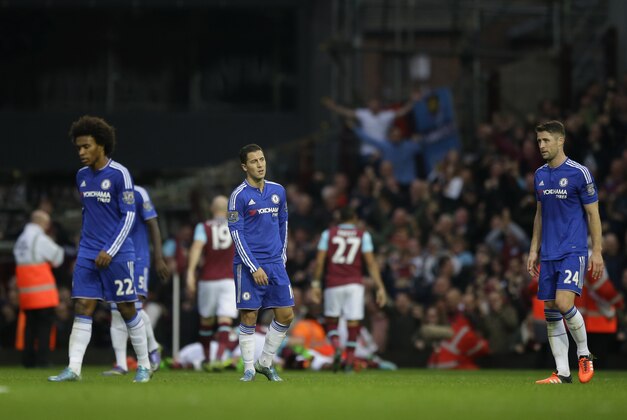 Chelsea's William, left, Eden Hazard, center, and Gary Cahill react as West Ham's Andy Carroll and his teammates celebrate their goal in the background during the English Premier League soccer match between West Ham and Chelsea at Upton Park stadium in London, Saturday, Oct. 24, 2015.  (AP Photo/Matt Dunham)