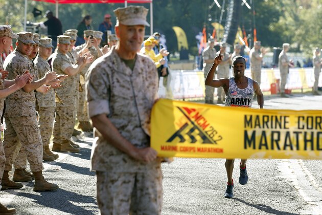 Samuel Kosgei, from Junction City, Kan., celebrates as he prepares to cross the finish line to be the first male finisher of the 39th Marine Corps Marathon, Sunday, Oct. 26, 2014 in Arlington, Va. The race includes runners from 59 nations and each branch of the U.S. armed forces.  (AP Photo/Alex Brandon)
