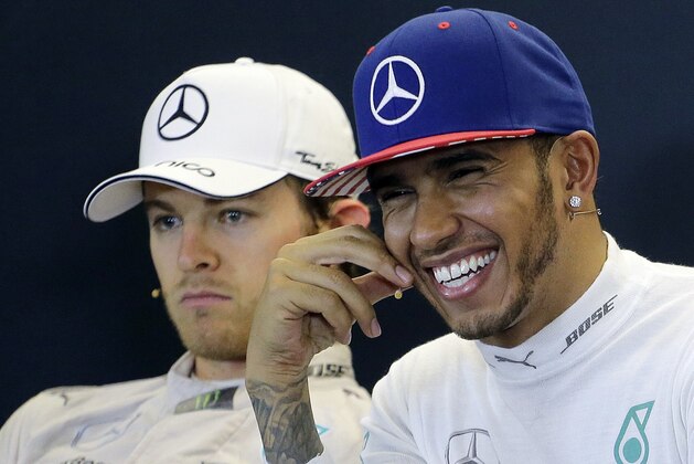 Mercedes driver Lewis Hamilton, of Britain, smiles during a news conference after winning the world championship with is victory at the Formula One U.S. Grand Prix auto race at the Circuit of the Americas, Sunday, Oct. 25, 2015, in Austin, Texas. Mercedes driver Nico Rosberg, of Germany, is at left.(AP Photo/Eric Gay)