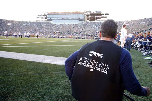 In this Oct. 10, 2015 photo, a Showtime film crew member works on the field during an NCAA college football game between Notre Dame  and Navy in South Bend, Ind. Showtime is filming a series “A Season With Notre Dame Football,” a behind the scenes show of what goes on during the week before the game _ and the game. (AP Photo/Jeff Haynes)