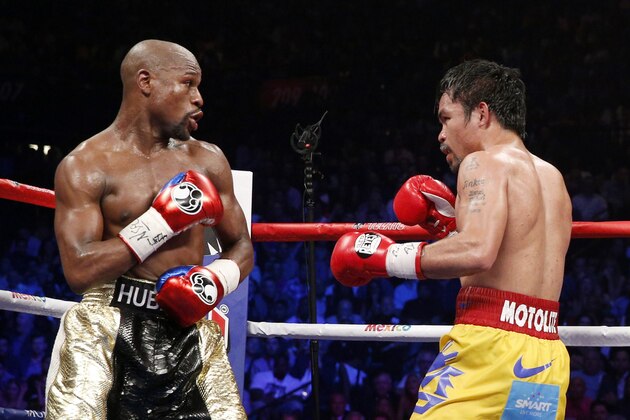 Floyd Mayweather Jr. exchange punches with Manny Pacquiao during their welterweight unification championship bout, May 2, 2015 at MGM Grand Garden Arena in Las Vegas, Nevada.  Mayweather defeated Pacquiao by unanimous decision.  AFP PHOTO / JOHN GURZINKSI        (Photo credit should read JOHN GURZINSKI/AFP/Getty Images)
