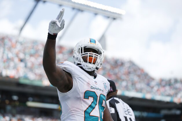 Miami Dolphins running back Lamar Miller (26) raises his hand after scoring a touchdown during the first half of an NFL football game against the Houston Texans, Sunday, Oct. 25, 2015 in Miami Gardens, Fla. The Dolphins defeated the Texans 44-26. (AP Photo/Joel Auerbach)