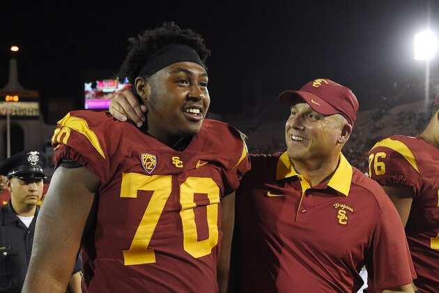 Southern California interim head coach Clay Helton, right, puts his arm around Southern California offensive tackle Chuma Edoga as they walk off the field after USC defeated Utah 42-24 in a NCAA college football game, Saturday, Oct. 24, 2015, in Los Angeles. (AP Photo/Mark J. Terrill)