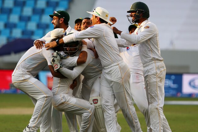 Pakistan's cricket players after they dismissed England's Adil Rashid to win the second Test cricket match between Pakistan and England in the Gulf emirate of Dubai on October 26, 2015. AFP PHOTO / MARWAN NAAMANI        (Photo credit should read MARWAN NAAMANI/AFP/Getty Images)