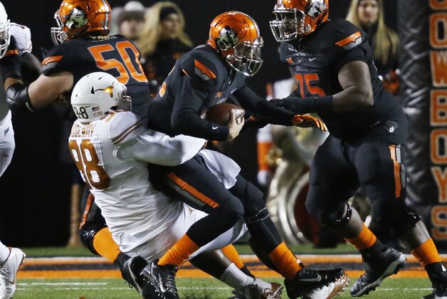Oklahoma State's Daxx Garman (12) is sacked by Texas Hassan Ridgeway (98) in the second quarter of an NCAA college football game in Stillwater, Okla., Saturday, Nov. 15, 2014. (AP Photo/Sue Ogrocki)