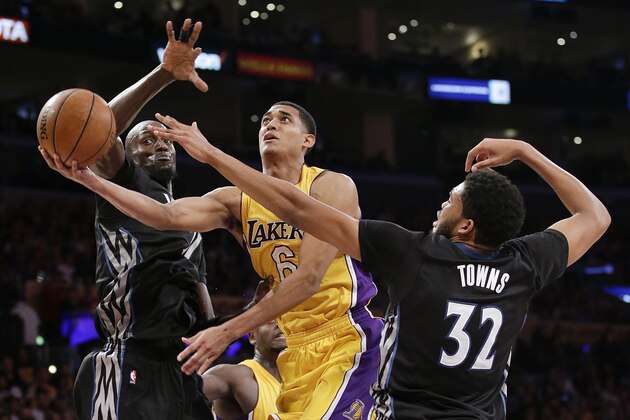 Los Angeles Lakers' Jordan Clarkson, center, goes up for a basket under pressure by Minnesota Timberwolves' Karl-Anthony Towns, right, and Kevin Garnett during the first half of an NBA basketball game, Wednesday, Oct. 28, 2015, in Los Angeles. (AP Photo/Jae C. Hong)