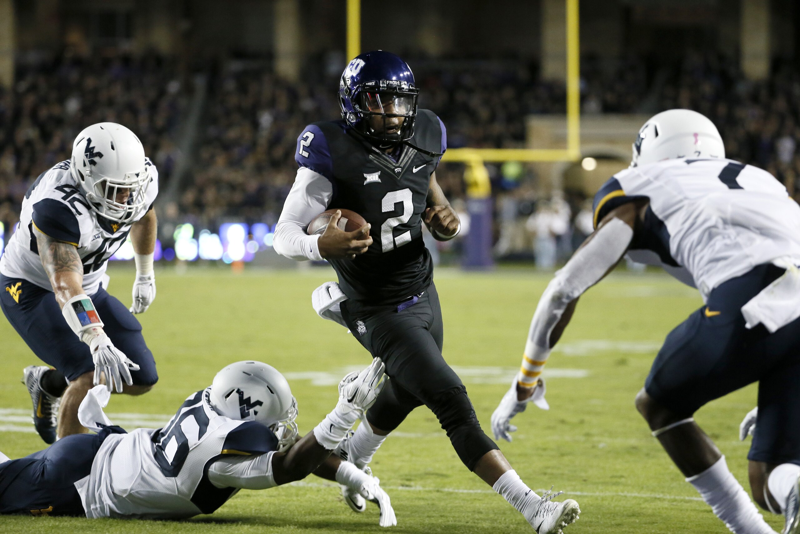 TCU quarterback Trevone Boykin (2) gets by West Virginia's Jared Barber (42) and Shaq Petteway, bottom, before leaping over cornerback Daryl Worley, right, into the end zone for a touchdown in the first half of an NCAA college football game Thursday, Oct. 29, 2015, in Fort Worth, Texas. (AP Photo/Tony Gutierrez) TCU quarterback Trevone Boykin (2) gets by West Virginia's Jared Barber (42) and Shaq Petteway, bottom, before leaping over cornerback Daryl Worley, right, into the end zone for a touchdown in the first half of an NCAA college football game Thursday, Oct. 29, 2015, in Fort Worth, Texas. (AP Photo/Tony Gutierrez)