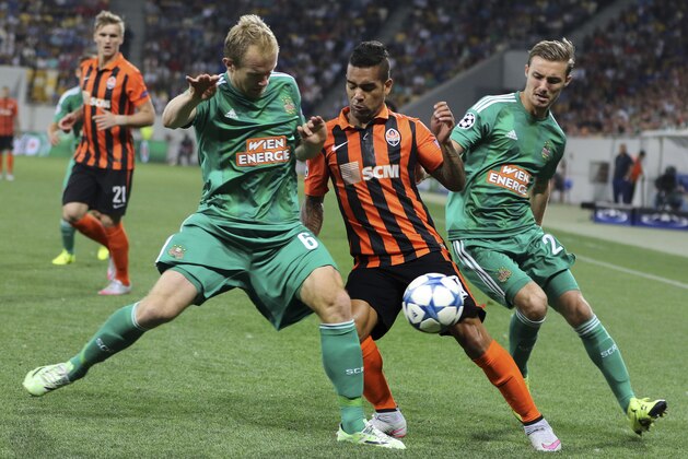 Rapid's Mario Sonnleitner, left,  Mario Pavelic, right, and Shakhtar's Alex Teixeira challenge for the ball during the Champions League play-off second leg soccer match between SK Rapid Wien and FC Shakhtar Donetsk in Lviv, Ukraine, Tuesday, Aug. 25, 2015. (AP Photo(AP Photo/Yevheniy Kravs)