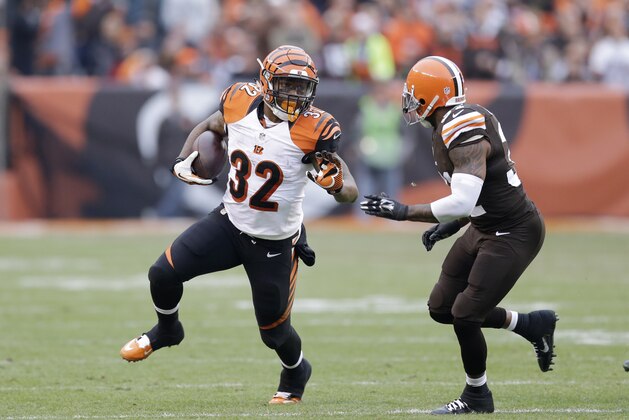 Cincinnati Bengals running back Jeremy Hill (32) avoids a tackle by Cleveland Browns defensive back Jim Leonhard (30) during an NFL football game Sunday, Dec. 14, 2014, in Cleveland. (AP Photo/Tony Dejak)