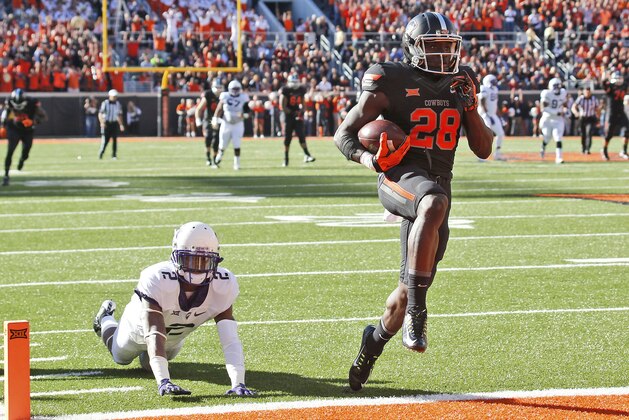 Oklahoma State wide receiver James Washington (28) carries a Mason Rudolph pass into the end zone for a touchdown in front of TCU cornerback Torrance Mosley (2) in the first quarter of an NCAA college football game in Stillwater, Okla., Saturday, Nov. 7, 2015. (AP Photo/Sue Ogrocki) Oklahoma State wide receiver James Washington (28) carries a Mason Rudolph pass into the end zone for a touchdown in front of TCU cornerback Torrance Mosley (2) in the first quarter of an NCAA college football game in Stillwater, Okla., Saturday, Nov. 7, 2015. (AP Photo/Sue Ogrocki)