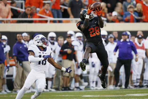 Oklahoma State wide receiver James Washington (28) leaps up for a pass in front of TCU safety Nick Orr (18) in the third quarter of an NCAA college football game in Stillwater, Okla., Saturday, Nov. 7, 2015. Washington took the pass into the end zone for a touchdown and Oklahoma State won 49-29. (AP Photo/Sue Ogrocki)