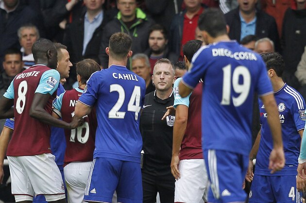 Chelsea and West Ham players surround referee Jonathan Moss (C) as he prepares to make a decision following a challenge by Chelsea's Serbian midfielder Nemanja Matic on West Ham United's Senegalese striker Diafra Sakho during the English Premier League football match between West Ham United and Chelsea at The Boleyn Ground in Upton Park, east London on October 24, 2015. AFP PHOTO / IAN KINGTON

RESTRICTED TO EDITORIAL USE. No use with unauthorized audio, video, data, fixture lists, club/league logos or 'live' services. Online in-match use limited to 75 images, no video emulation. No use in betting, games or single club/league/player publications.        (Photo credit should read IAN KINGTON/AFP/Getty Images)