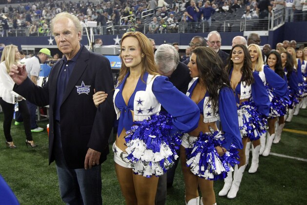 Dallas Cowboys Ring of Honor member Roger Staubach, left,  is escorted by a Dallas Cowboys Cheerleader during an NFL football game Sunday, Nov. 1, 2015, in Arlington, Texas. (AP Photo/Michael Ainsworth)