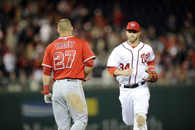 Washington Nationals left fielder Bryce Harper (34) runs from the field past Los Angeles Angels' Mike Trout (27) during the seventh inning of a baseball game, Monday, April 21, 2014, in Washington. The Angels won 4-2. (AP Photo/Nick Wass)
