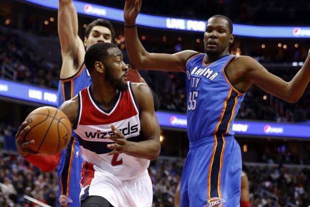 Washington Wizards guard John Wall (2) passes the ball in front of Oklahoma City Thunder center Steven Adams (12), from New Zealand, and forward Kevin Durant (35) in the second half of an NBA basketball game, Wednesday, Jan. 21, 2015, in Washington. The Thunder won 105-103 in overtime. (AP Photo/Alex Brandon)