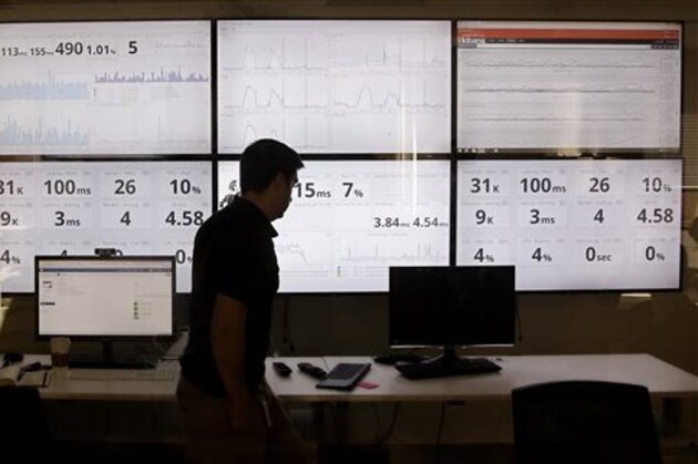 FILE - In this Sept. 9, 2015 file photo, an employee in the software development department of DraftKings, a daily fantasy sports company, walks past screens displaying the company's online system stats in Boston.  Customers of the two biggest daily fantasy sports websites have filed at least four lawsuits against the sites in Oct. 2015, following cheating allegations and a probe into the largely-unregulated multi-billion dollar industry. In court papers, the customers accused the DraftKings and FanDuel sites of cheating, and argued they never would have played had they known employees with insider knowledge were playing on rival sites.  (AP Photo/Stephan Savoia)