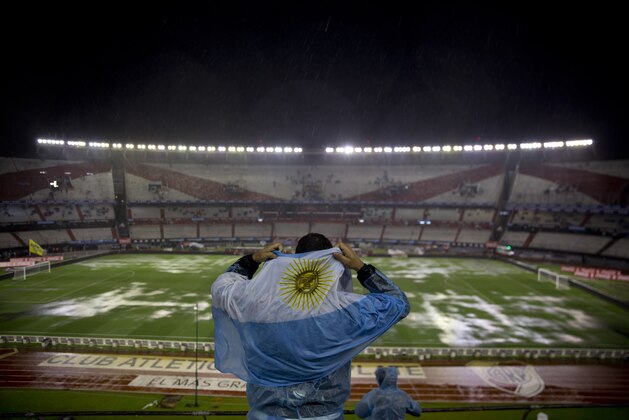 An Argentina soccer fan in the stands of the Antonio Vespucio Liberti stadium, covers himself from the pouring rain, before a 2018 World Cup qualifying soccer match against Brazil, in Buenos Aires, Argentina, Thursday, Nov. 12, 2015. (AP Photo/Natacha Pisarenko)