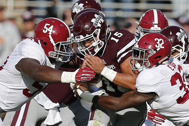 Mississippi State quarterback Dak Prescott (15) is tackled by Alabama defensive lineman Dalvin Tomlinson (54) and linebacker Rashaan Evans (32) during the first half of an NCAA college football game in Starkville, Miss., Saturday, Nov. 14, 2015. (AP Photo/Rogelio V. Solis)