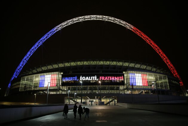 The arch of Wembley Stadium in London, is seen lit up in the colors of the French flag above the words translated from French