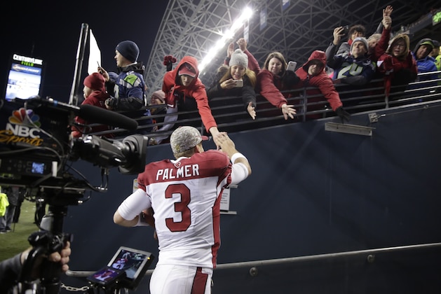 Arizona Cardinals quarterback Carson Palmer greets fans as he leaves the field after an NFL football game against the Seattle Seahawks, Sunday, Nov. 15, 2015, in Seattle. The Cardinals beat the Seahawks 39-32. (AP Photo/Stephen Brashear)