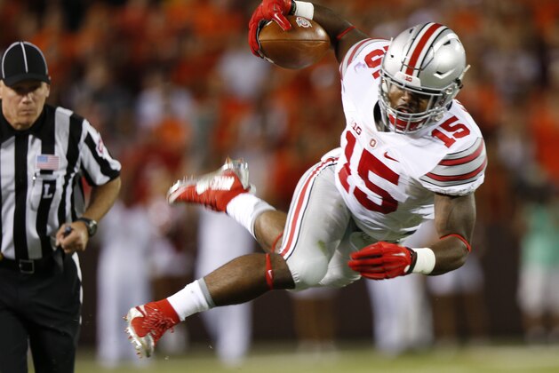 Ohio State running back Ezekiel Elliott (15) jumps over Virginia Tech safety Desmond Frye (26)  during the first half of an NCAA college football game in Blacksburg, Va., Monday, Sept. 7, 2015.   (AP Photo/Steve Helber)