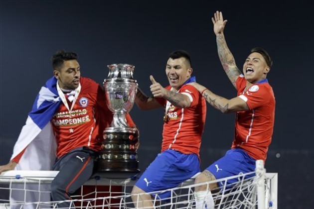 Chile's Gary Medel, center, and Chile's Eduardo Vargas, right, hold the trophy on top of the goal post after defeating Argentina in the Copa America final soccer match at the National Stadium in Santiago, Chile, Saturday, July 4, 2015. Chile became Copa America champions for the first time after defeating Argentina in a penalty shootout. (AP Photo/Ricardo Mazalan)