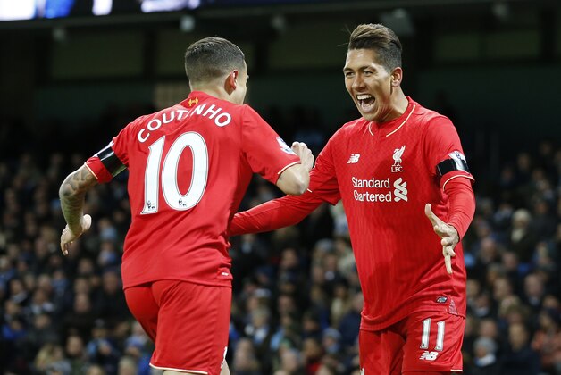 Liverpool’s Roberto Firmino celebrates with teammate Liverpool’s Philippe Coutinho after his cross which is then turned in by Manchester City's Eliaquim Mangala who scores an own goal for the opening goal of the game during the English Premier League soccer match between Manchester City and Liverpool at the Etihad Stadium, Manchester, England, Saturday, Nov. 21, 2015. (AP Photo/Jon Super)