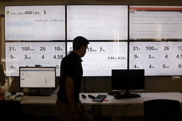 FILE - In this Sept. 9, 2015 file photo, an employee in the software development department of DraftKings, a daily fantasy sports company, walks past screens displaying the company's online system stats in Boston. Top daily fantasy sports companies are fiercely rejecting the idea that their rapidly-growing industry should be considered gambling in the United States. But FanDuel and DraftKings are OK with that label in the United Kingdom. They’re embracing it as a step toward global expansion. U.K. gambling regulators granted a gambling license to DraftKings in August, while FanDuel applied earlier this month for a license as a “gambling software” company. (AP Photo/Stephan Savoia, File)