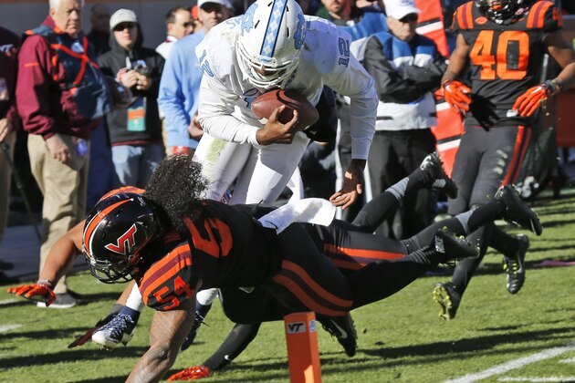 North Carolina quarterback Marquise Williams (12) dives toward the end zone as Virginia Tech linebacker Andrew Motuapuaka (54) defends during the second half of an NCAA college football game in Blacksburg, Va., Saturday, Nov. 21, 2015.  Williams was short of the goal liine.   UNC won the game 30-27 in overtime. (AP Photo/Steve Helber)