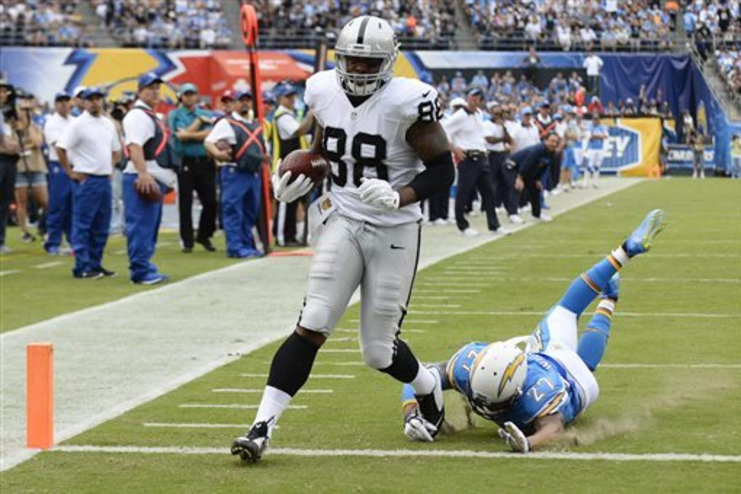 CORRECTS TO RAIDERS TIGHT END CLIVE WALFORD NOT WIDE RECEIVER AMARI COOPER - Oakland Raiders tight end Clive Walford, left, scores a touchdown as San Diego Chargers strong safety Jimmy Wilson (27) cannot reach him during the first half of an NFL football game Sunday, Oct. 25, 2015, in San Diego. (AP Photo/Denis Poroy)