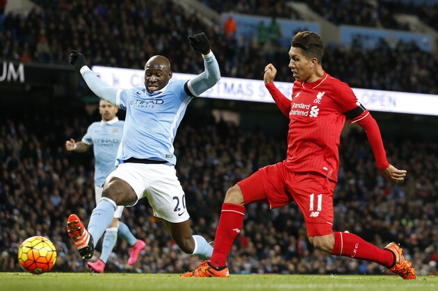 Liverpool’s Roberto Firmino, right shoots and scores his sides third goal of the game as Manchester City's Eliaquim Mangala attempts to block during the English Premier League soccer match between Manchester City and Liverpool at the Etihad Stadium, Manchester, England, Saturday, Nov. 21, 2015. (AP Photo/Jon Super)