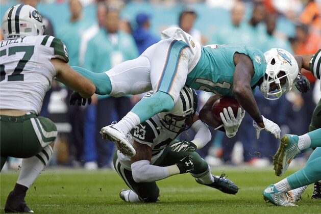 Miami Dolphins' Jarvis Landry, top right, is sent sprawling by a tackle during an NFL football game against the New York Jets at Wembley Stadium in London, Sunday, Oct. 4, 2015. (AP Photo/Matt Dunham)