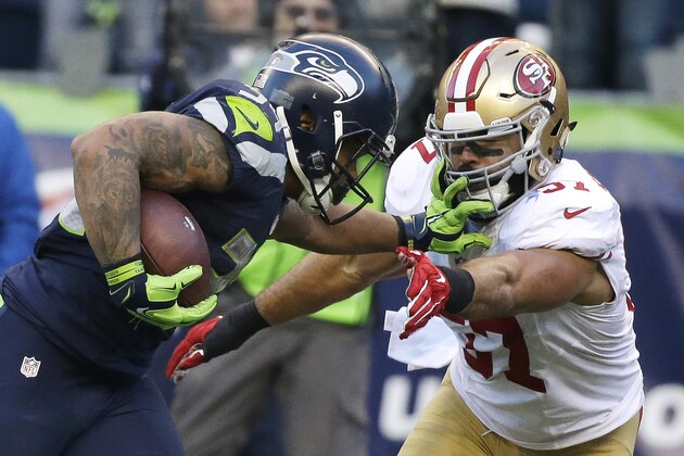 Seattle Seahawks running back Thomas Rawls, left, pushes off San Francisco 49ers inside linebacker Michael Wilhoite, right, as he runs for a touchdown during the second half of an NFL football game, Sunday, Nov. 22, 2015, in Seattle. (AP Photo/Elaine Thompson)